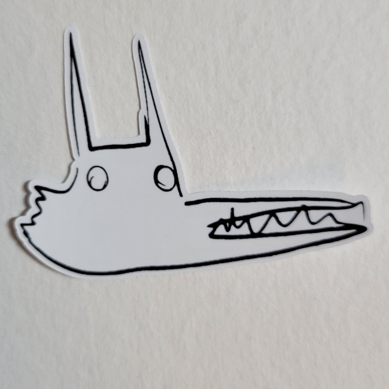 A die-cut sticker featuring a minimalist black line art illustration of a wolf on a white background, shown on a textured off-white surface.